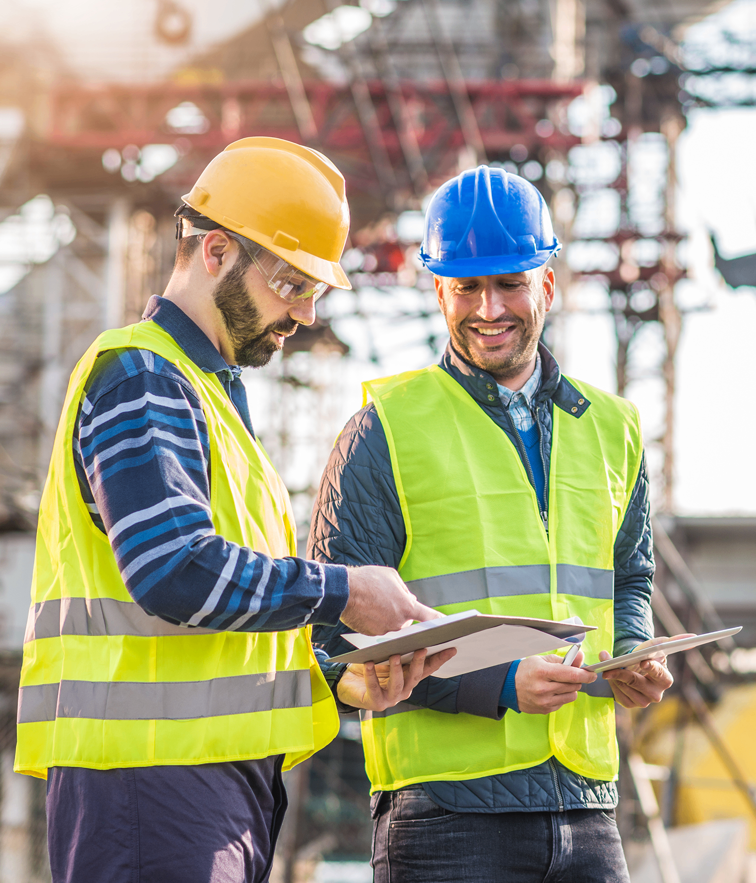 Two construction workers in hi-vis vests reviewing a tablet